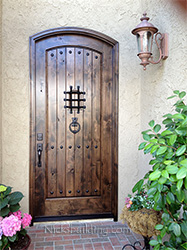 arched exterior door in rustic knotty alder with speakesy door and wrought iron grill